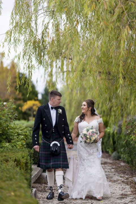 bride and groom with scottish kiln walking in the garden